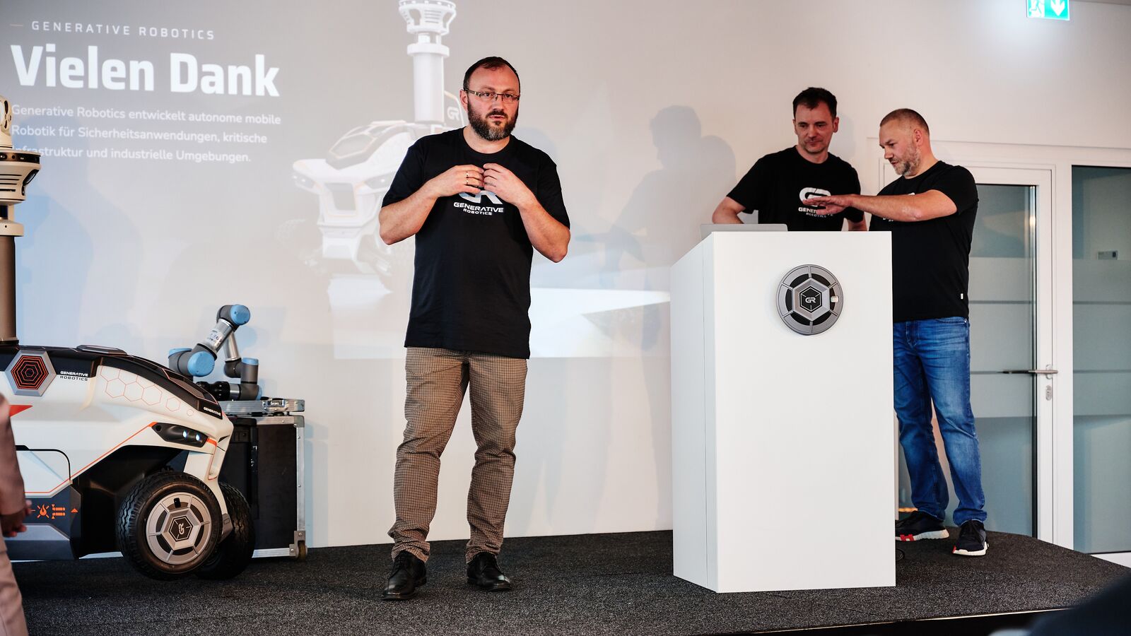 Aleksej Tokarev spricht auf der Bühne, am Rednerpult Thomas Schröter und Andreas Ciborius, links der GR-01